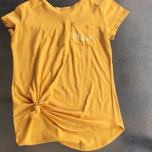Yellow shirt with pocket and writing.